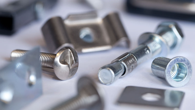 Verschiedene Metallbefestigungen wie Schrauben, Bolzen und Klemmelemente auf einer Oberfläche